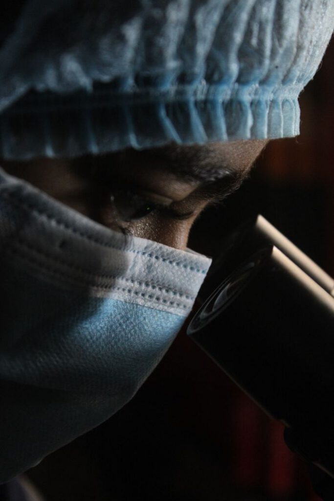 Close-up of a scientist analyzing samples under a microscope in a laboratory setting.